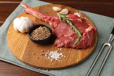 Photo of Raw ribeye steak, spices and fork on table