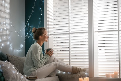 Young woman with hot drink at home. Cozy winter