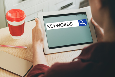 Image of Woman with tablet searching for keywords at table, closeup