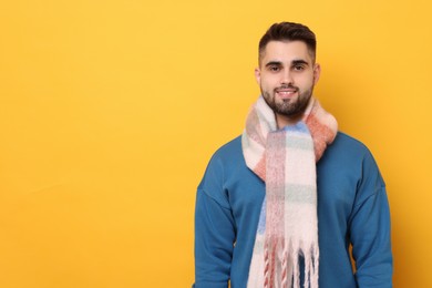 Photo of Smiling man in warm scarf on yellow background. Space for text