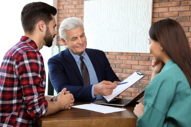 Senior notary working with young couple in office