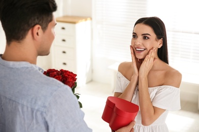 Photo of Man presenting gift to his beloved woman at home. Valentine's day celebration