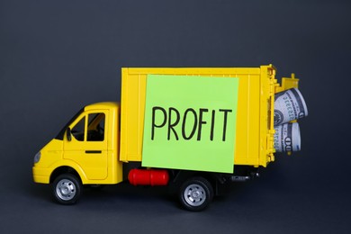 Photo of Economic profit concept. Toy truck with banknotes on black background