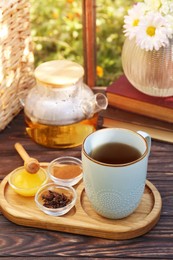 Tray with delicious tea and ingredients on wooden table