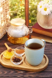 Photo of Tray with delicious tea and ingredients on wooden table