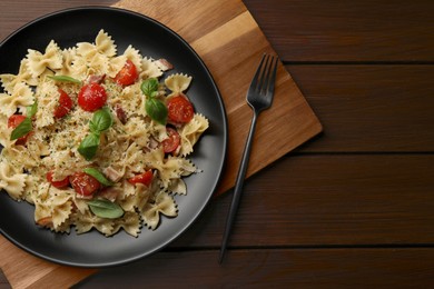 Photo of Delicious pasta with tomatoes, basil and parmesan cheese on wooden table, top view. Space for text