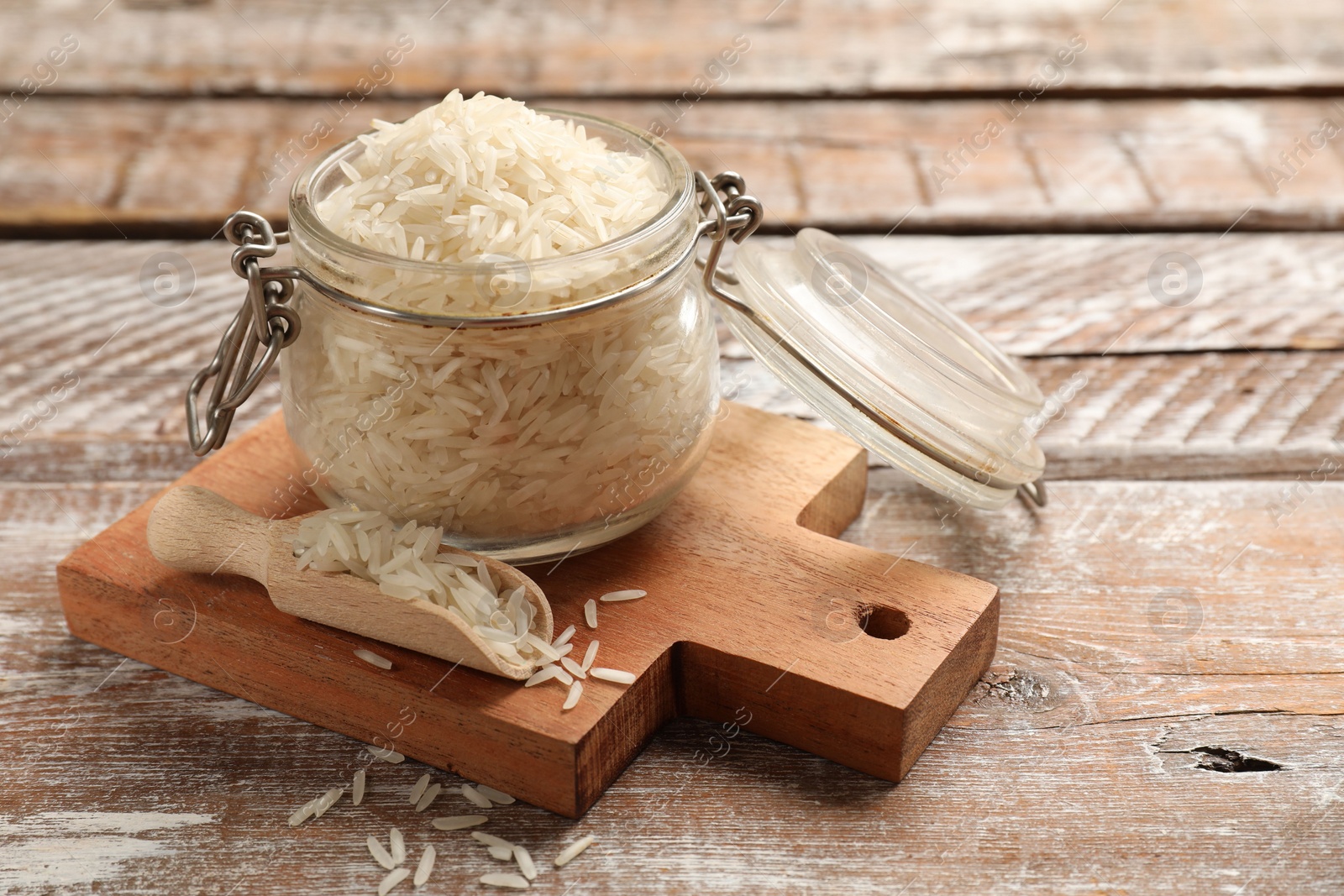 Photo of Raw basmati rice in glass jar and scoop on wooden table