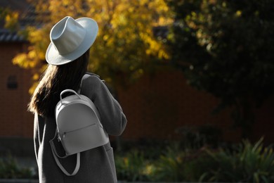 Photo of Young woman with stylish white backpack on city street, back view. Space for text