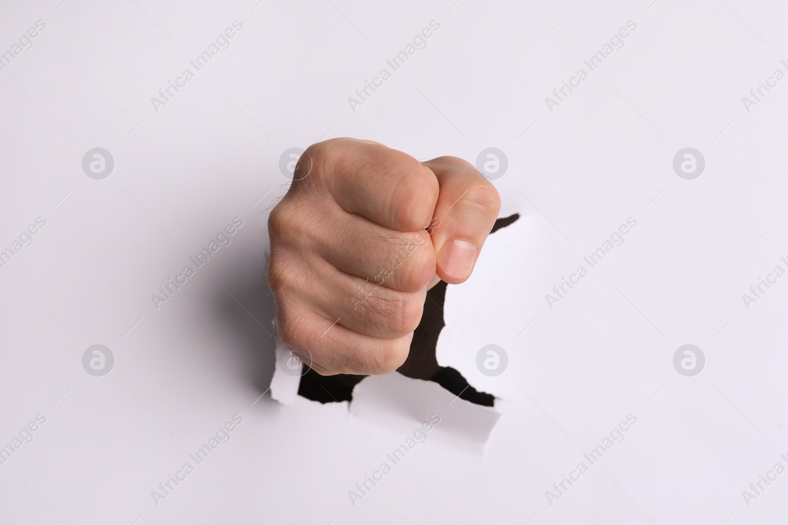 Photo of Man breaking through white paper with fist, closeup