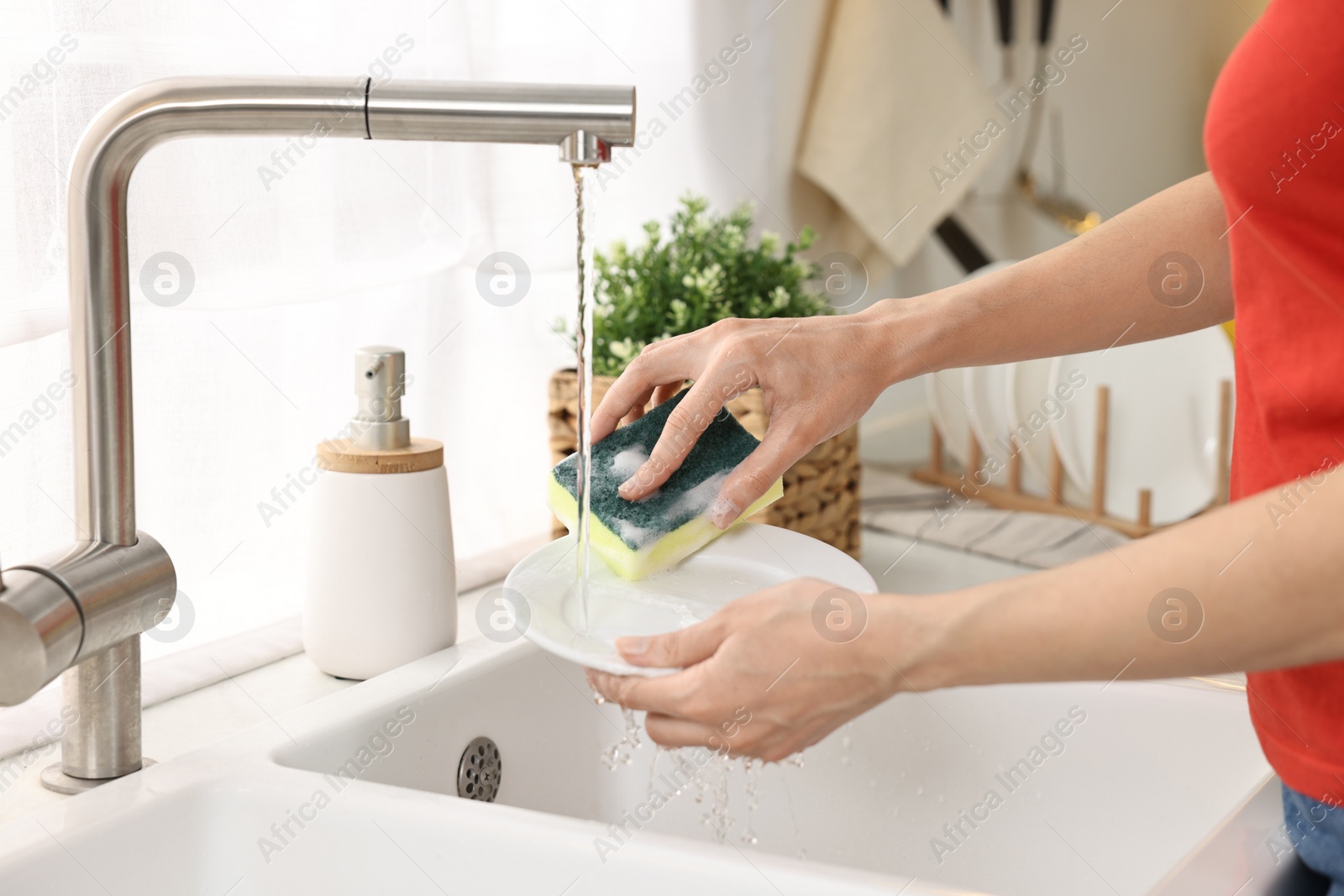 Photo of Woman washing dishes in kitchen sink, closeup. Cleaning chores