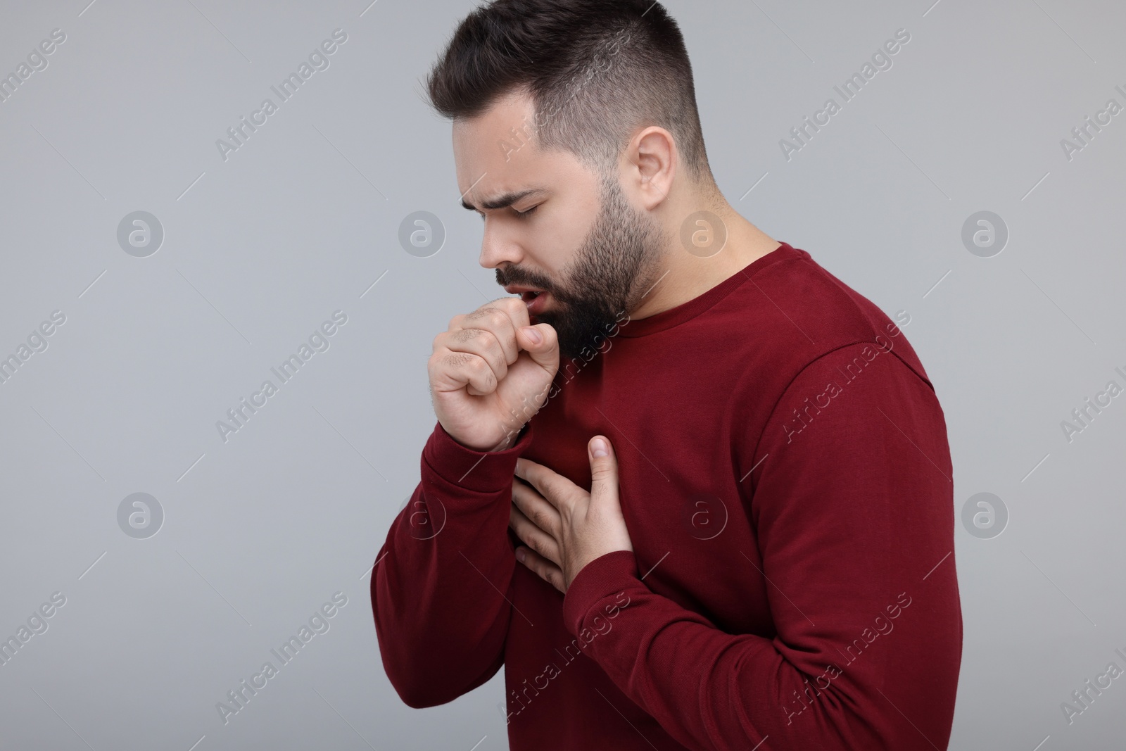 Photo of Sick man coughing on gray background, space for text