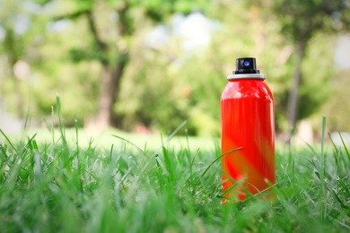 Bottle of insect repellent spray on grass. Space for text