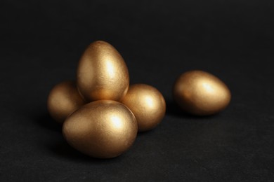 Many shiny golden eggs on black background