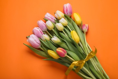 Photo of Bouquet of beautiful tulips on orange background, top view