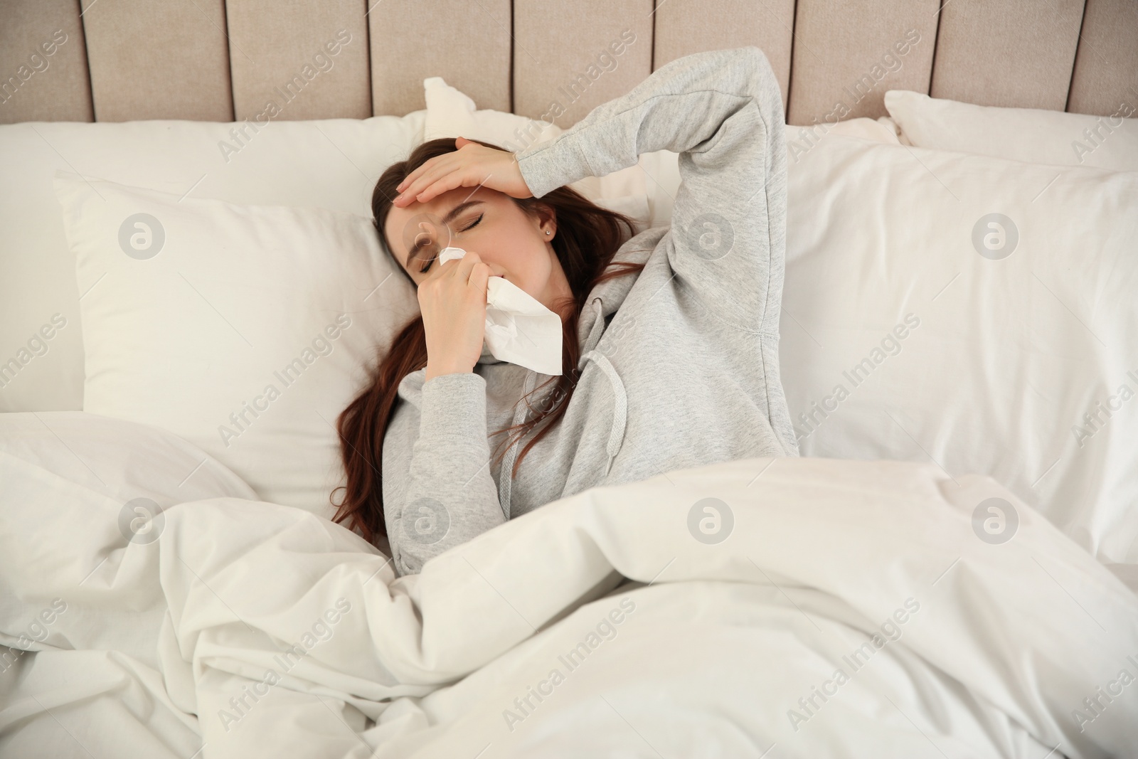 Photo of Sick young woman in bed at home. Influenza virus