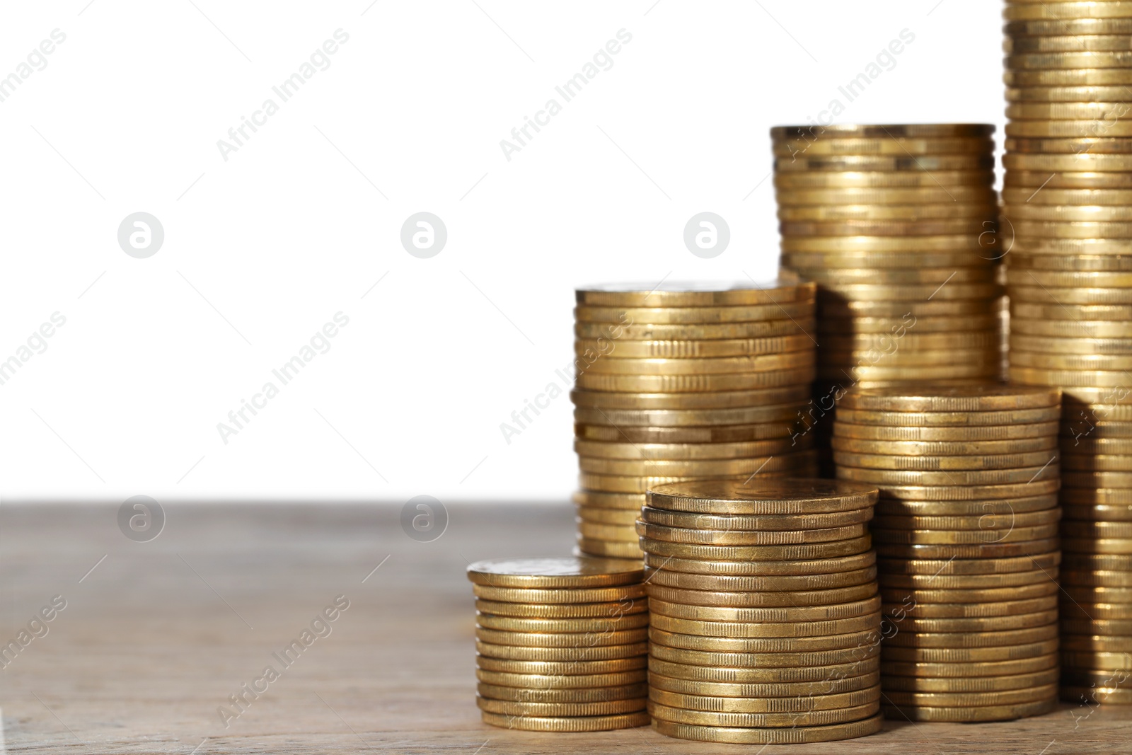 Photo of Many golden coins stacked on wooden table against white background