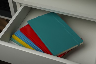 Photo of Stack of colorful planners in open drawer, closeup