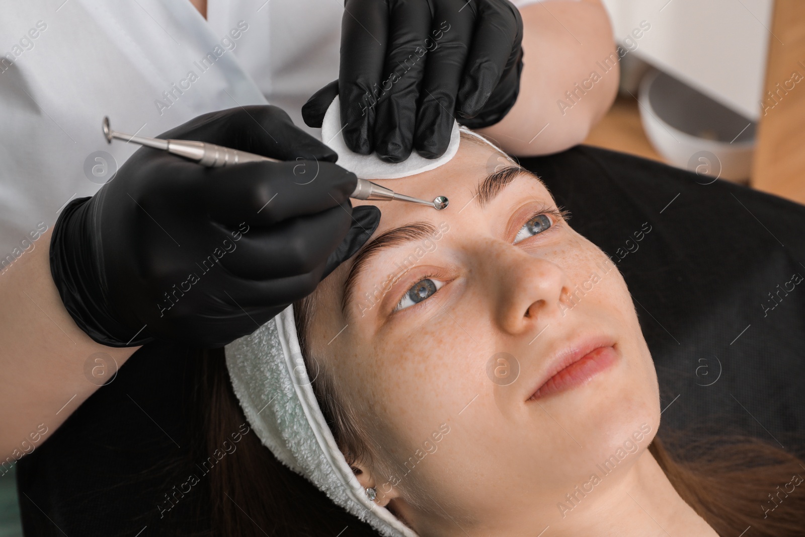 Photo of Cosmetologist using scrubber, closeup. Client having cleansing procedure