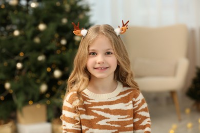 Photo of Portrait of cute girl wearing Christmas hair clips at home