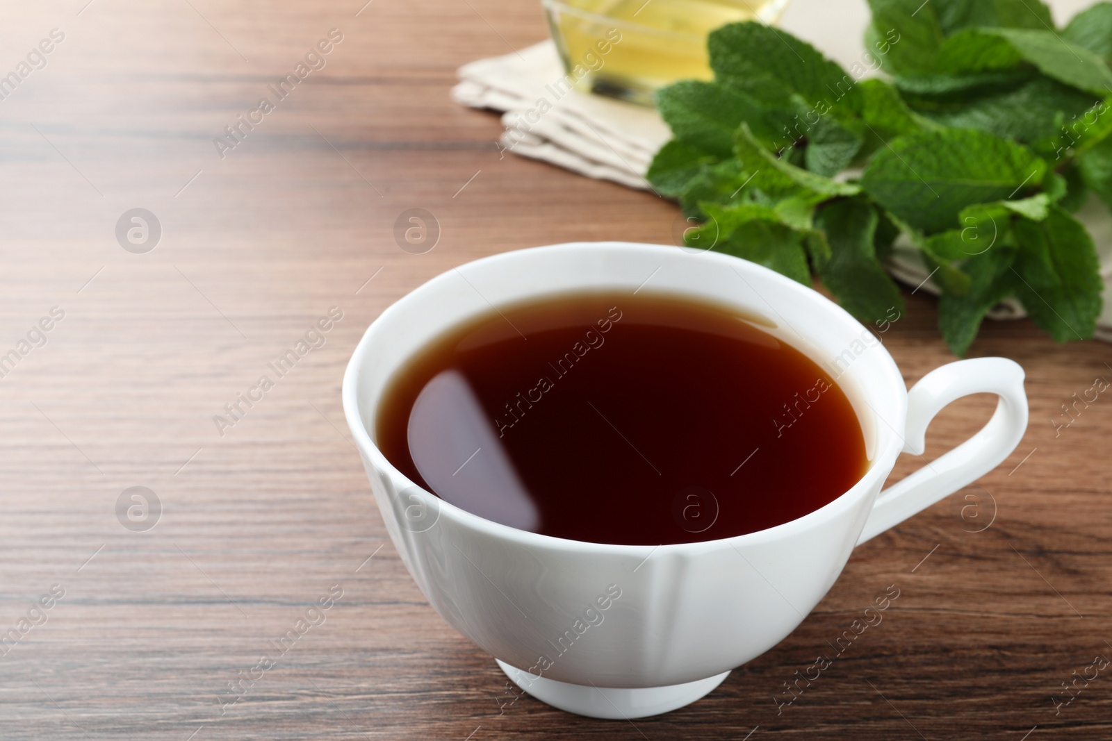 Photo of Cup of hot aromatic tea with mint on wooden table