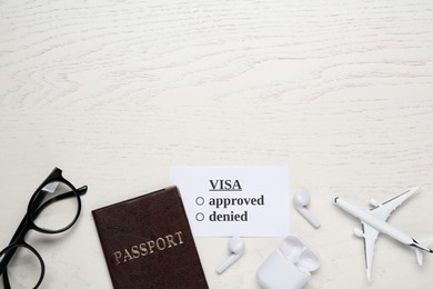 Photo of Flat lay composition with passport, toy plane and glasses on white wooden table, space for text. Visa receiving