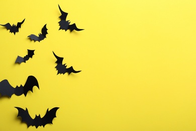 Photo of Paper bats on yellow background, flat lay with space for text. Halloween decor