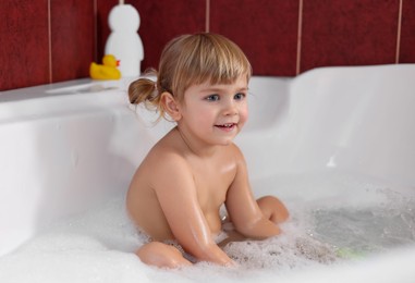 Smiling girl bathing in tub at home