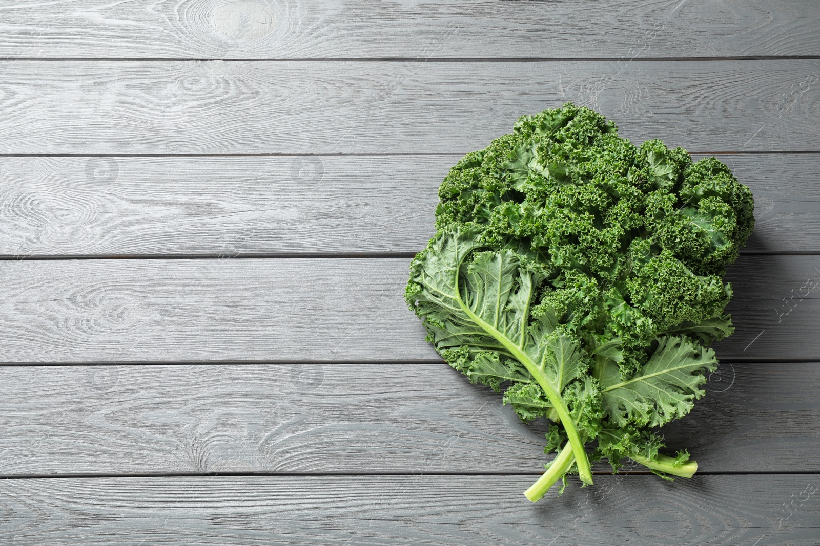 Photo of Fresh kale leaves on light grey wooden table, top view. Space for text