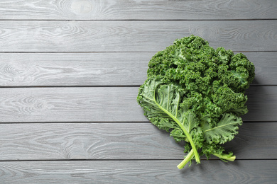 Fresh kale leaves on light grey wooden table, top view. Space for text