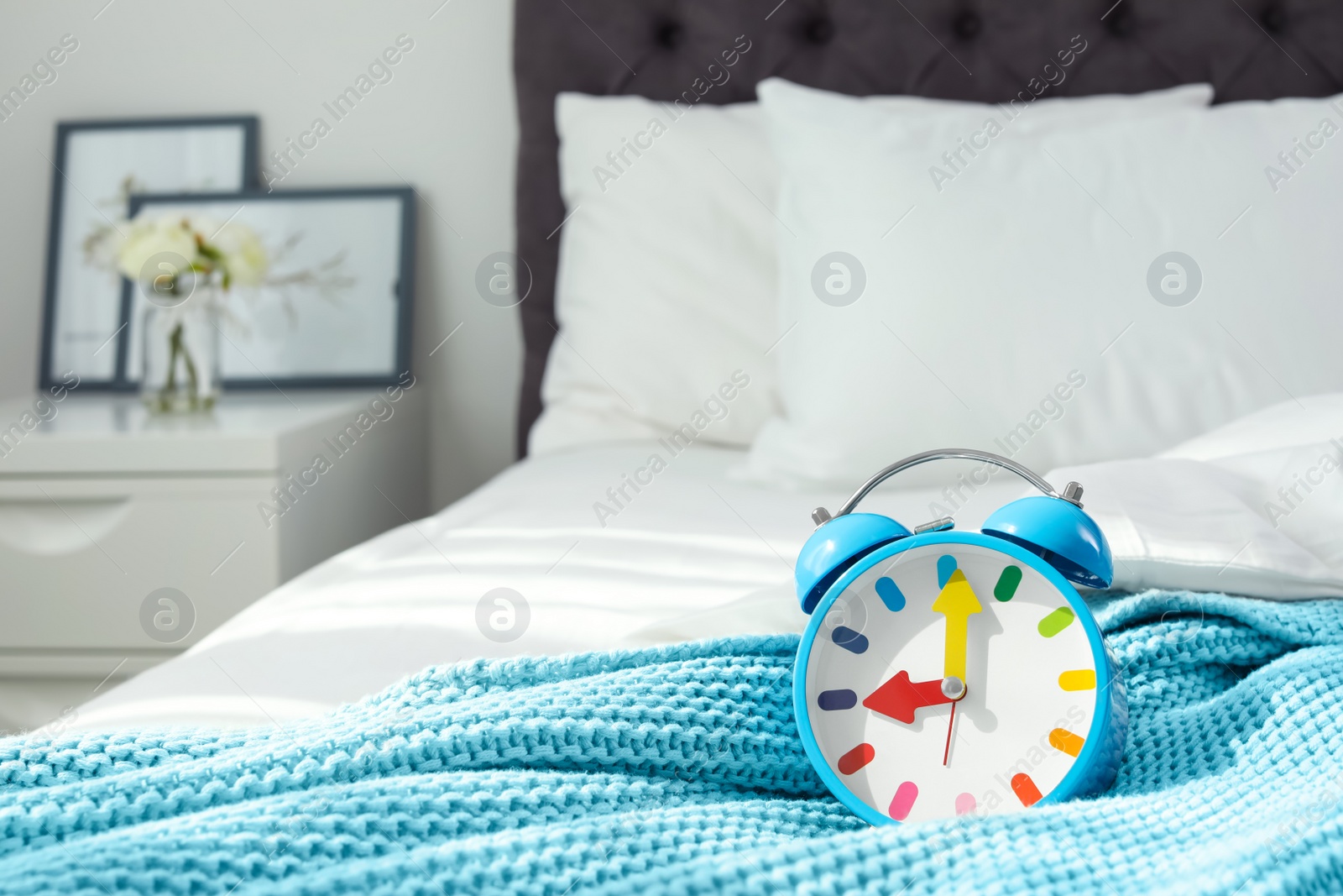 Photo of Colorful alarm clock on bed. Time to wake up