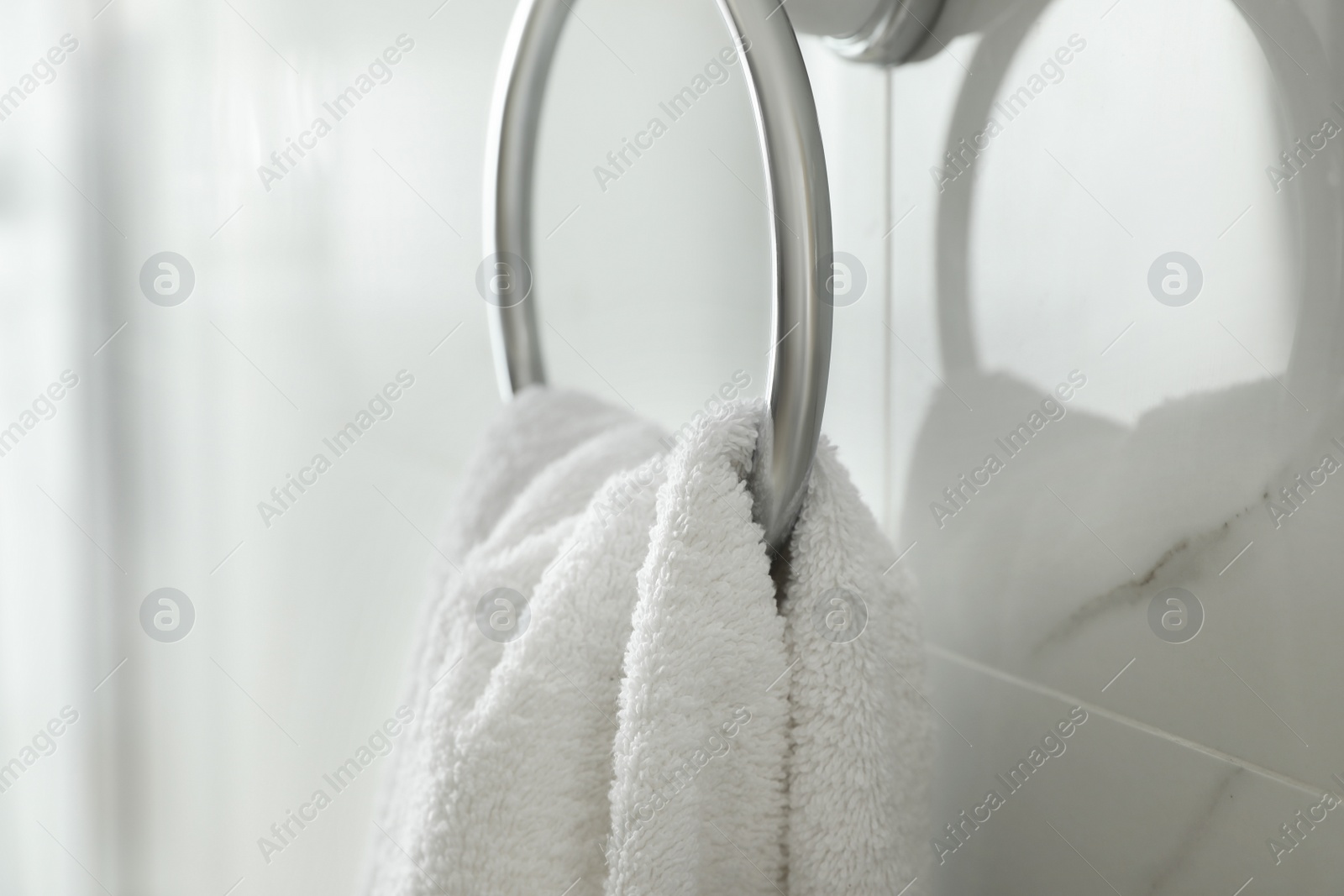 Photo of Holder with clean towel on light wall in bathroom