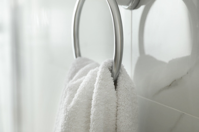 Photo of Holder with clean towel on light wall in bathroom