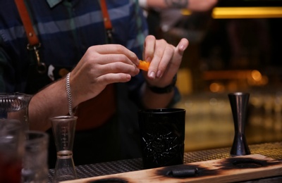 Photo of Bartender preparing tasty cocktail at counter in nightclub, closeup