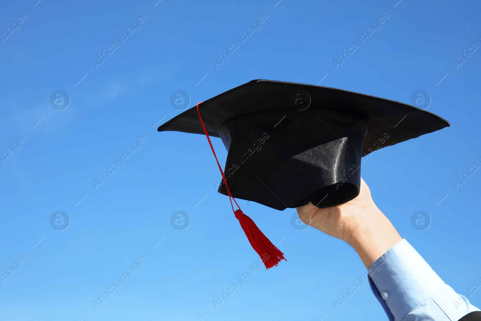 Photo of Student with graduation hat and blue sky on background, closeup