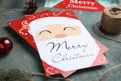 Photo of Christmas card and festive decor on light blue wooden background, closeup