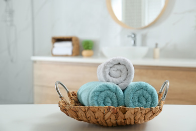 Photo of Wicker tray with clean soft towels in bathroom. Space for text