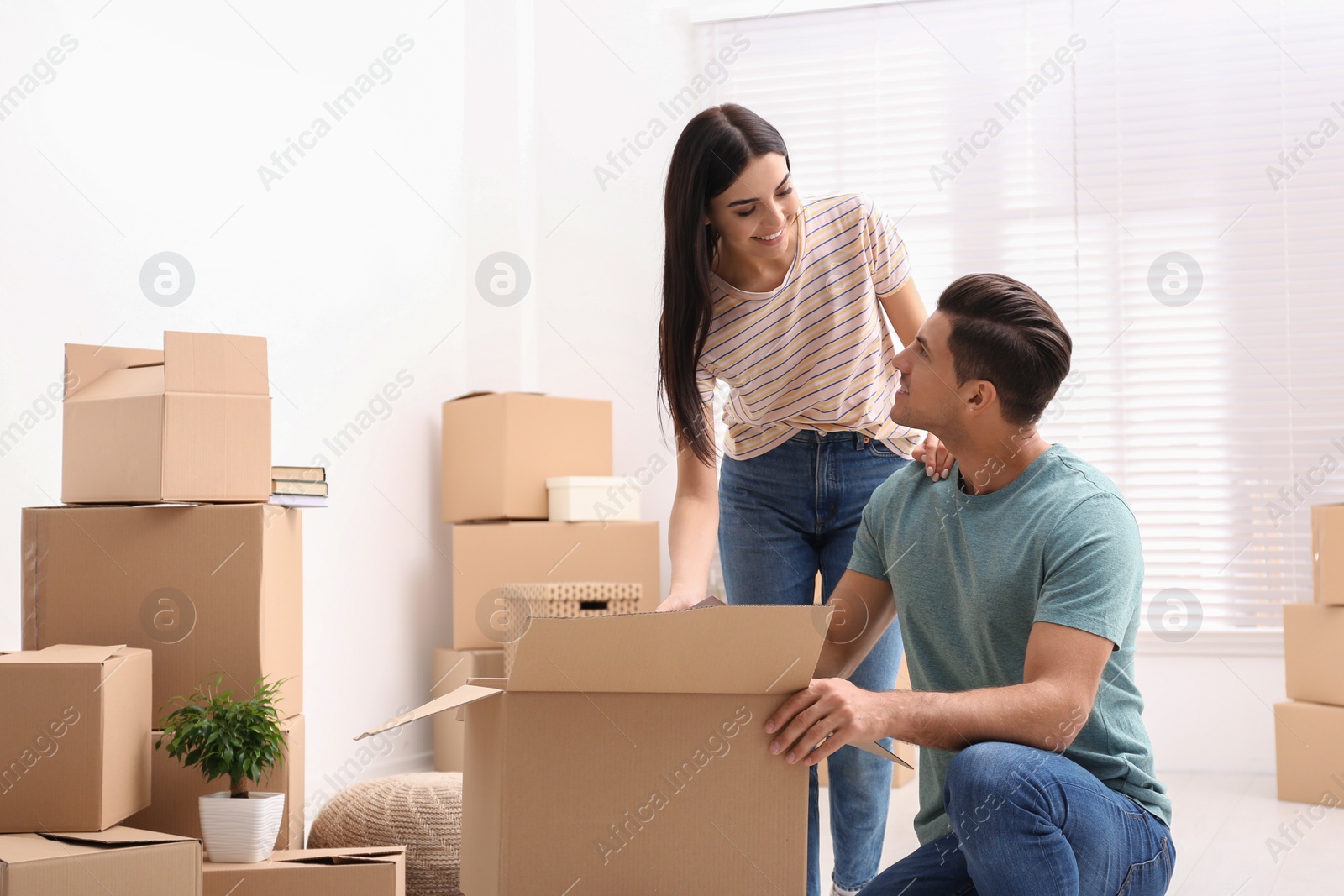 Photo of Happy couple unpacking cardboard boxes in their new flat on moving day