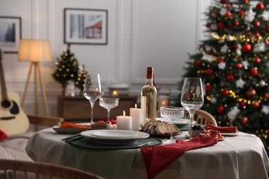 Christmas table setting with burning candles, appetizers and dishware in room