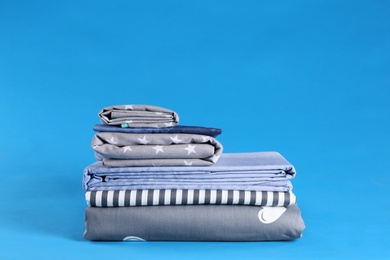 Photo of Stack of clean bed sheets on blue background