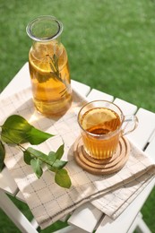 Glass bottle and cup of tasty iced tea on white table