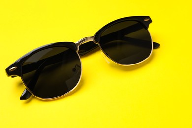 Photo of New stylish elegant sunglasses on yellow background