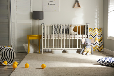 Photo of Cute baby room interior with crib and decor elements