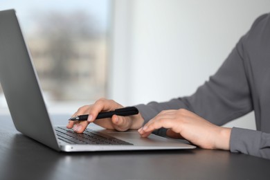 Photo of Woman working on laptop at table, closeup. Electronic document management