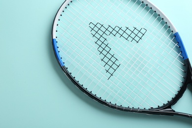 Tennis racket on light blue background, top view. Sports equipment