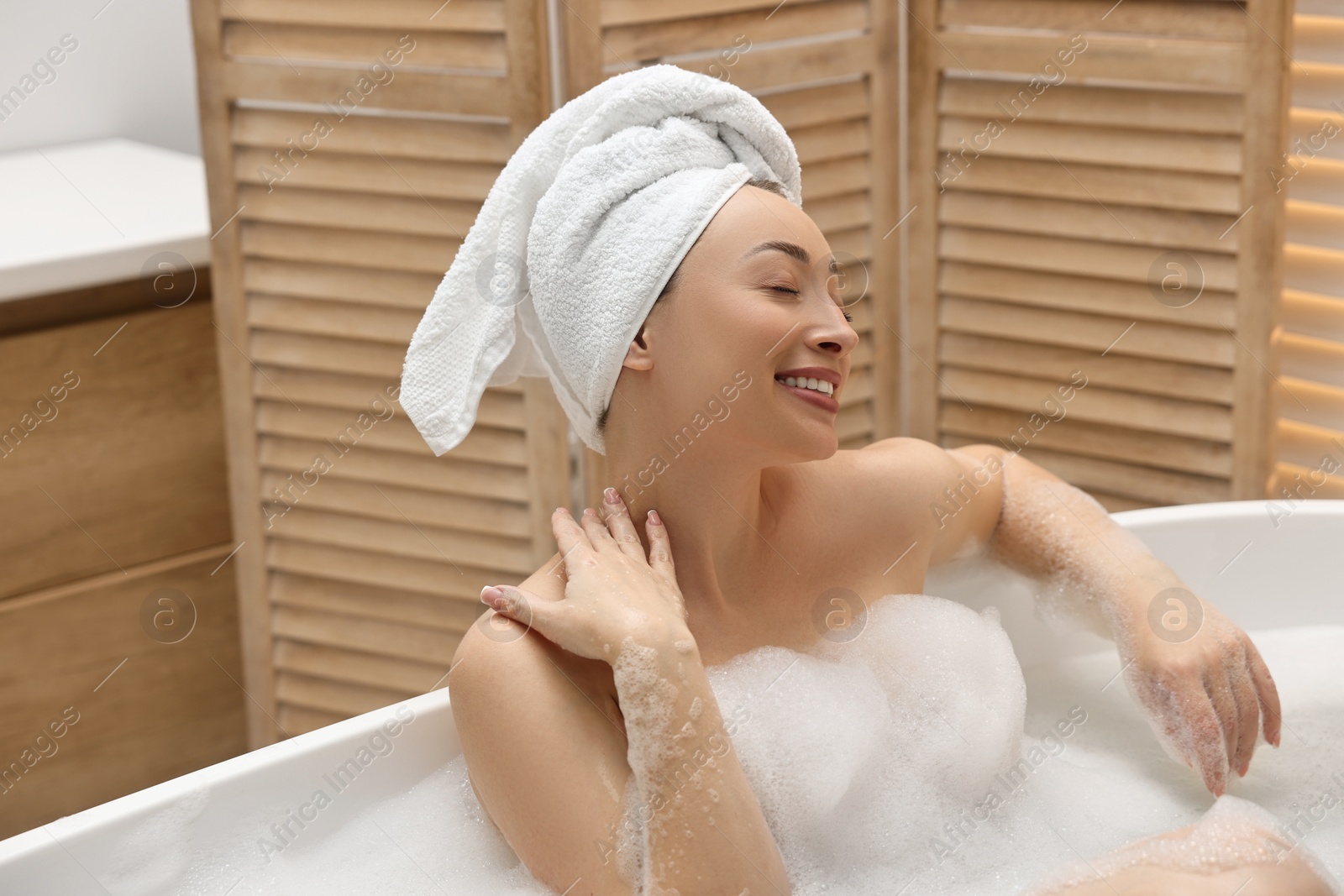 Photo of Beautiful woman taking bath with foam in tub indoors, space for text