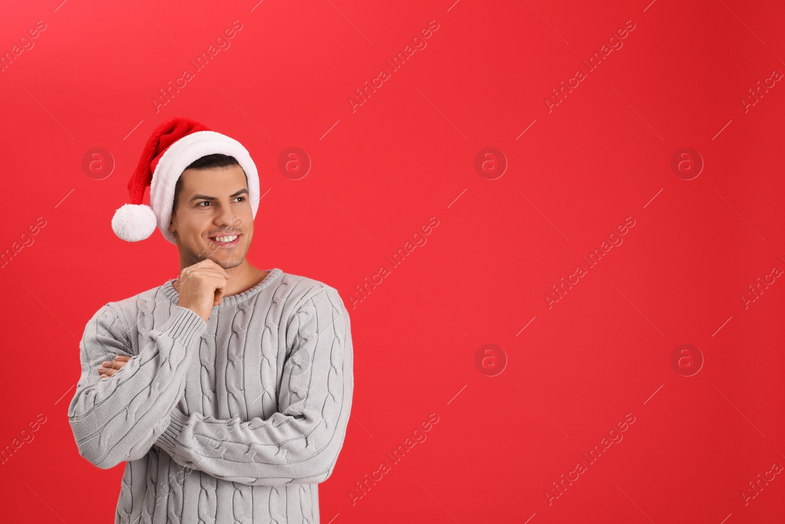 Photo of Handsome man wearing Santa hat on red background, space for text