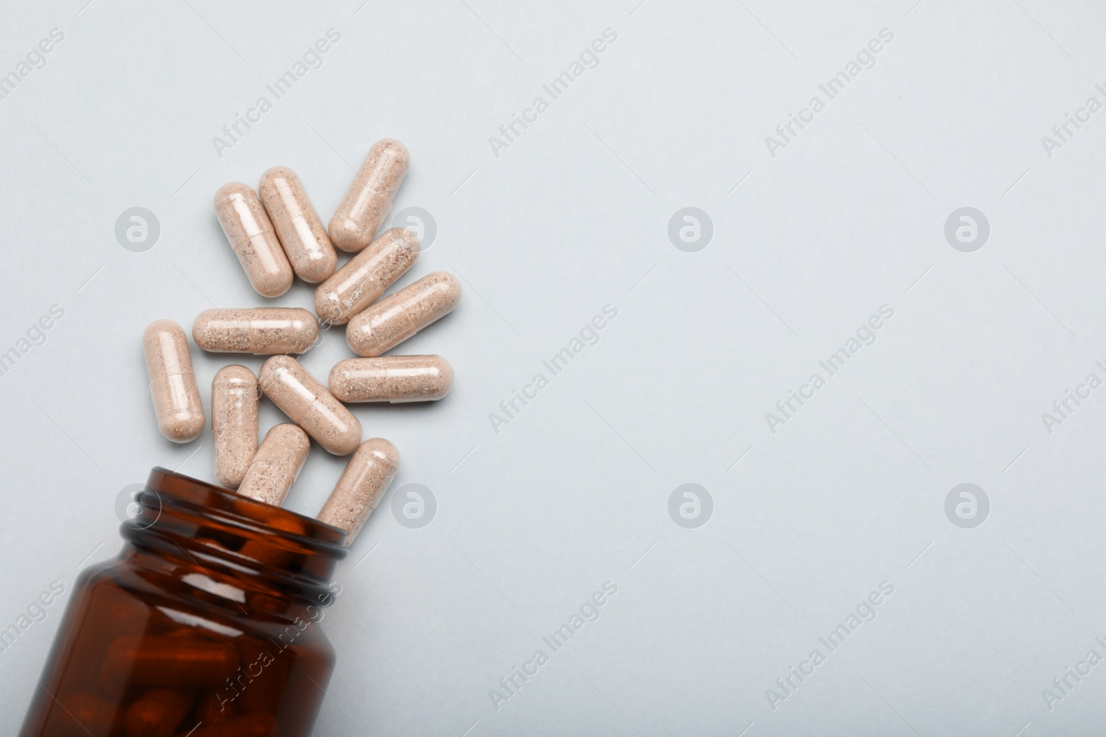 Photo of Many gelatin capsules and bottle on light grey background, flat lay. Space for text