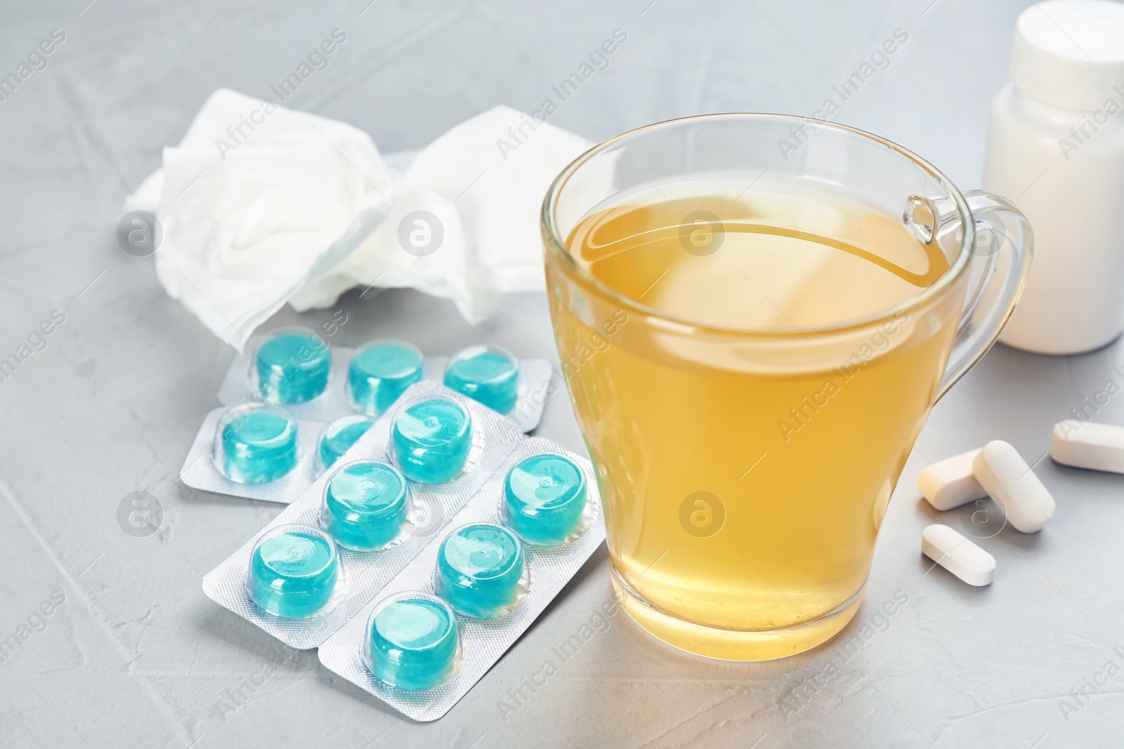 Photo of Cup with hot tea, pills and drugs for cold on table