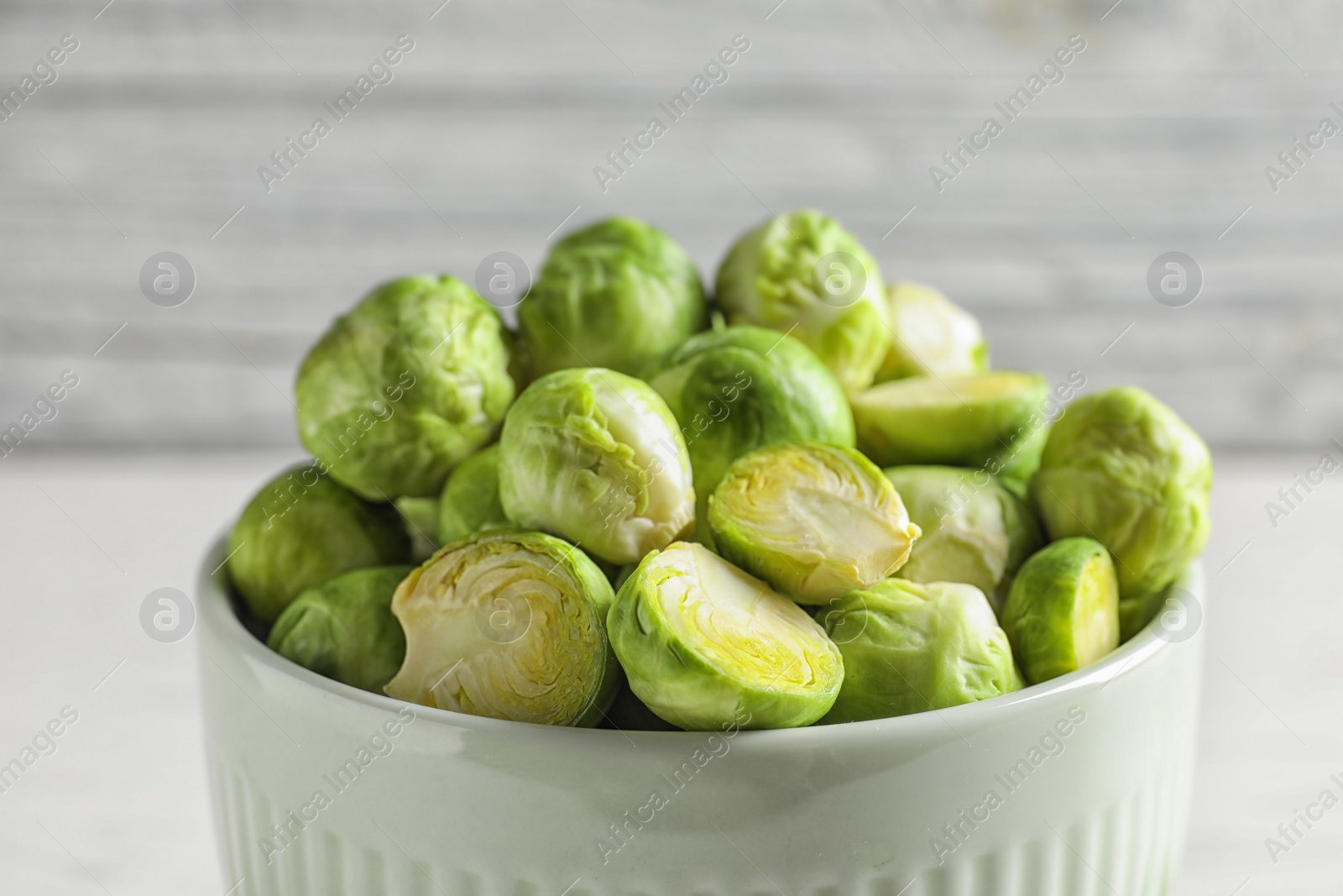 Photo of Bowl of fresh Brussels sprouts on blurred background, closeup