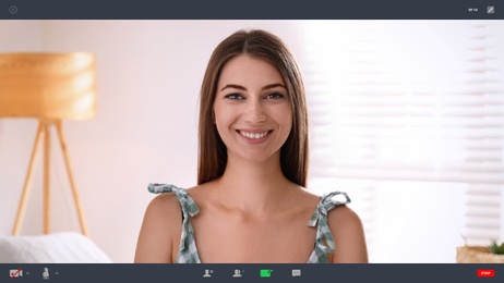 Image of Woman communicating with coworkers from home using video chat, view through camera